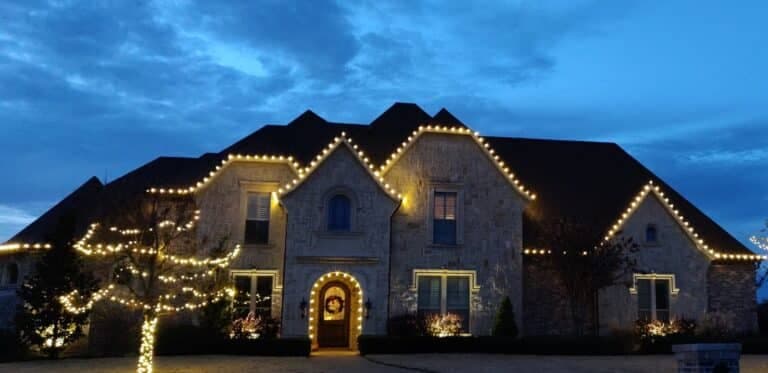 Beautifully lit stone house adorned with festive lights against a twilight sky.