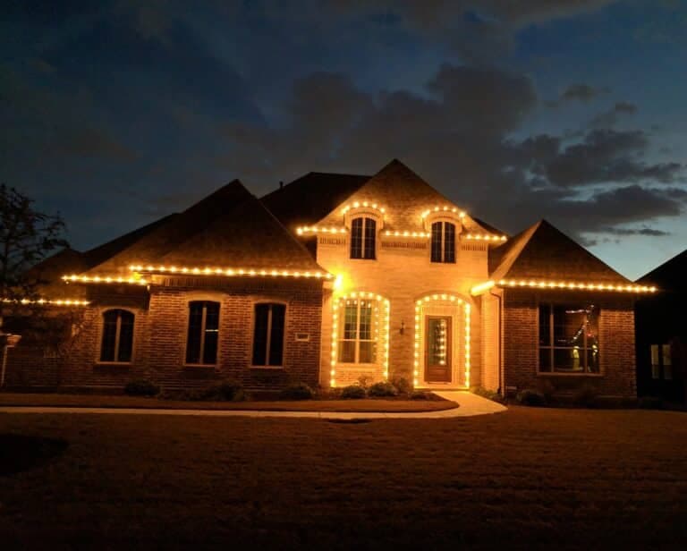 Elegant home adorned with warm lights at dusk, showcasing festive holiday spirit.