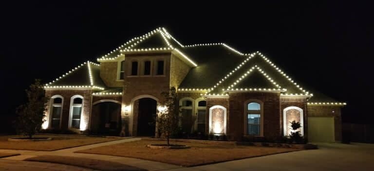 Elegant brick house adorned with dazzling LED lights at night, showcasing festive holiday spirit.