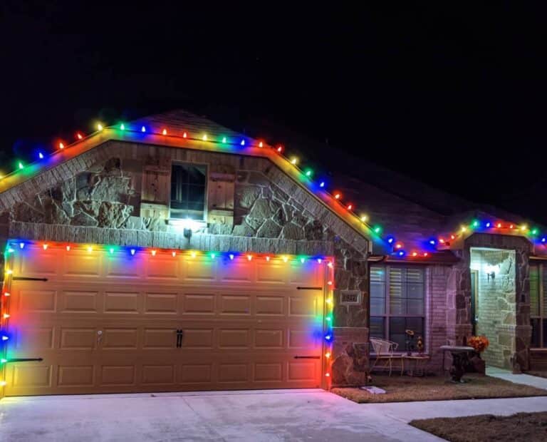 Decorated house with vibrant colorful Christmas lights illuminating the exterior at night.
