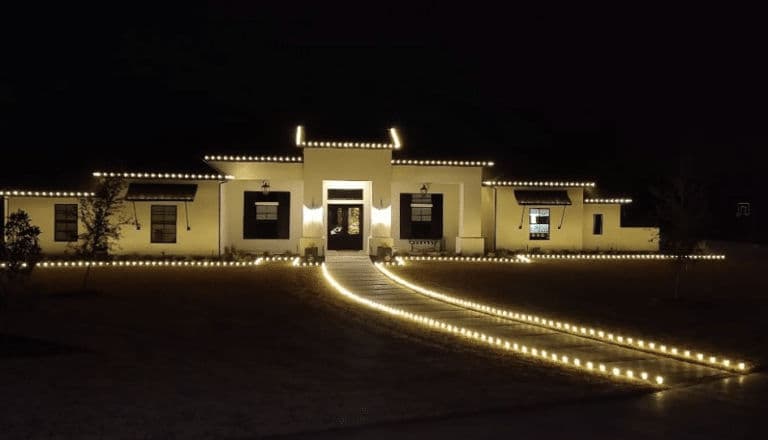 Modern home illuminated with decorative lights along the walkway at night.