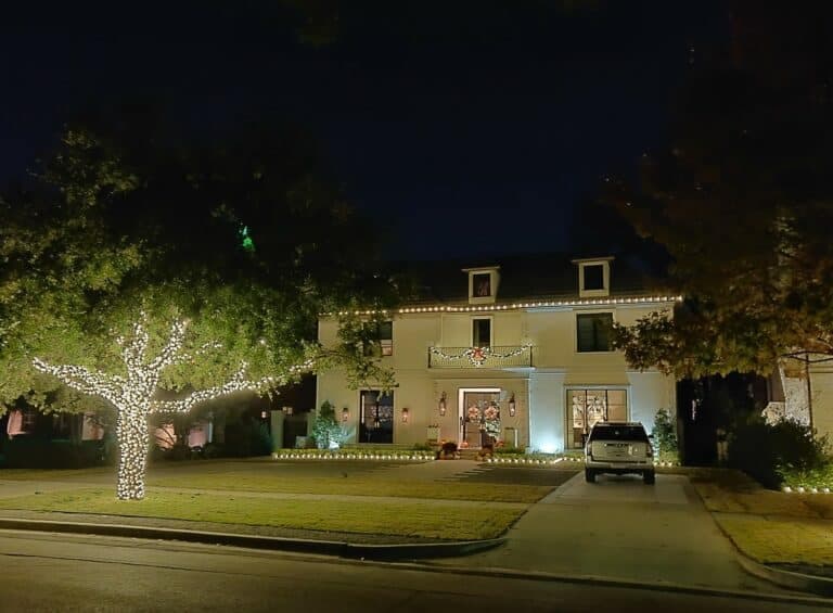 Festively decorated house with holiday lights and a tree at night.