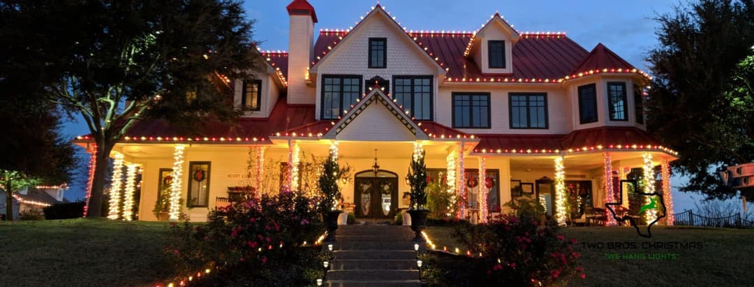 Festively decorated house with Christmas lights and vibrant landscaping at twilight.