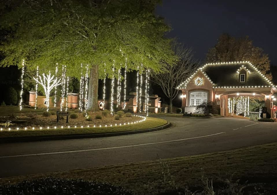Elegant holiday lights adorn a beautiful home entrance at night, enhancing festive ambiance.