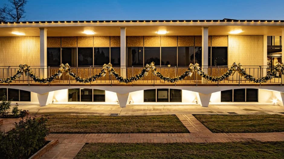 Festively decorated building with golden bows and garlands illuminated at dusk.