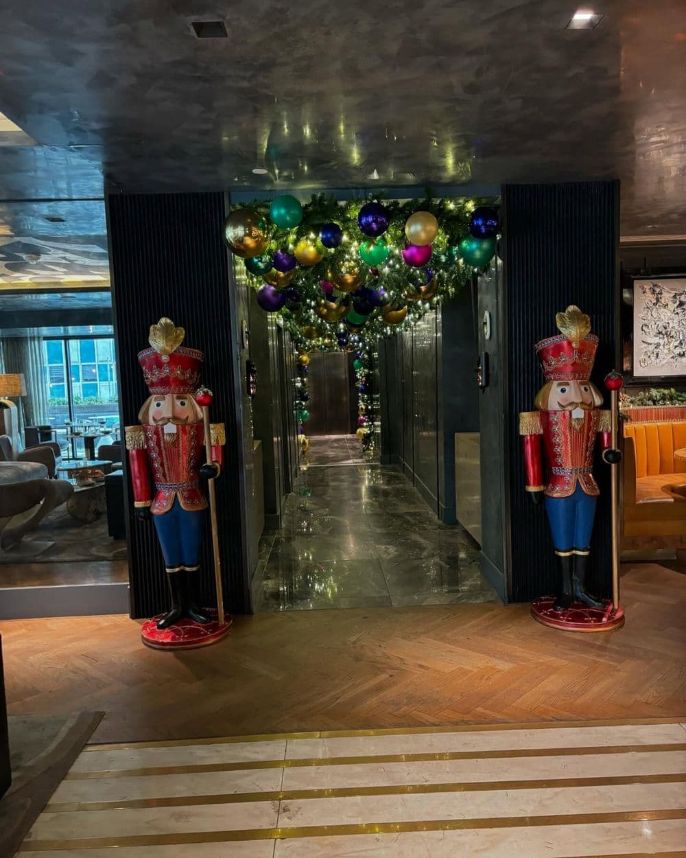 Nutcracker decorations flanking a festive hallway adorned with colorful balloons and lights.